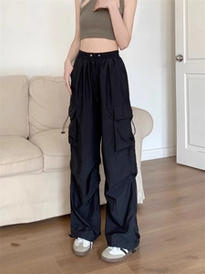 Detail of black cargo pants featuring functional side pockets and adjustable drawstring waist