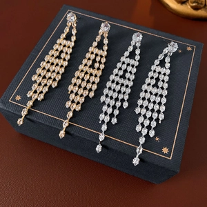 Detail of long tassel earrings in gold and silver finish with sparkling drop zircon stones