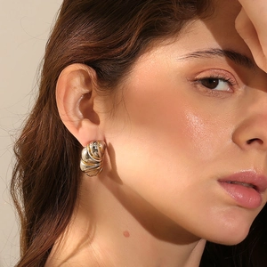 Détail des boucles d'oreilles bicolores plaquées or 18 carats avec texture rayée sur modèle