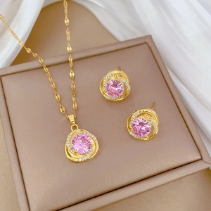 Detailed set of golden necklace and stud earrings with pink stones on silk