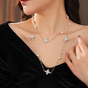 Gros plan détaillé d'un collier argenté à deux rangs avec perles et éléments floraux