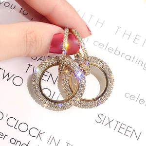 Macro shot of hand-held gold double hoop earrings with pavé rhinestones and luxury finish
