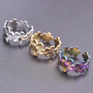 Macro shot of colorful floral steel rings with adjustable open bands in multi-tone finish