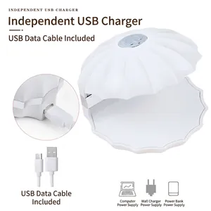Vista detallada de la lámpara LED de uñas con forma de concha blanca y cable de carga USB