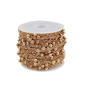 Macro view of gold-plated flat cross bead chain on a white spool for jewelry making