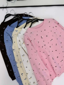 Row of five colorful crew neck floral knit sweaters hanging on a minimalist rack