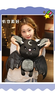 Close-up of a black bat plush toy with yellow moon embroidery and faux leather wings