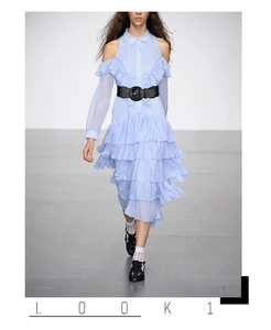 Detail of a wide elastic black belt with round buckle on a light blue ruffled dress