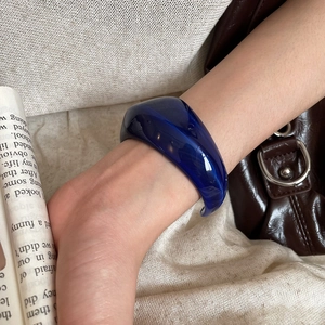 Close-up of a chunky dark blue acrylic irregular open bangle on a model's wrist