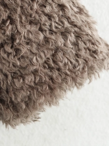 Detailed macro view of dark brown curly faux fur texture on a stylish autumn jacket