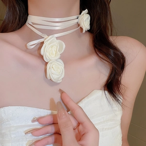 Detail of white fabric rose choker featuring elegant mesh ribbons and floral accents
