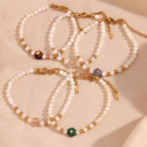 Detail of stainless steel bracelets with white beads and engraved gemstone charms