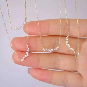 Detailed close-up showing four gold curved smile necklaces with small pavé diamonds held by hand