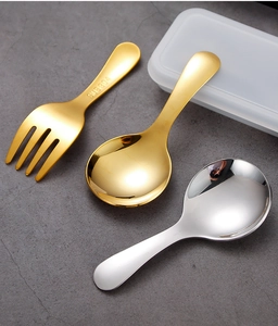 Close-up of golden and silver SUS 304 stainless steel mini spoons and fork on a stone surface