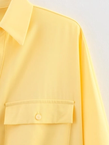 Detailed close-up of yellow twill shirt featuring lapel collar and flap chest pocket