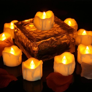 Detail of warm yellow LED candles with melted wax design and red flower petals