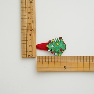 Green glittering Christmas tree hair clip with festive ornaments and red felt backing