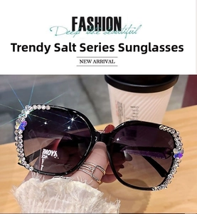 Détail de lunettes de soleil noires oversize avec strass brillants et papillons violets