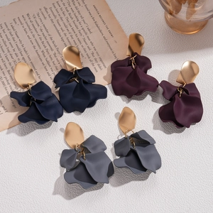 Petal-shaped acrylic earrings in navy, purple, and grey with golden studs on vintage paper