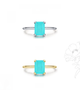 Detail of silver and gold rings with emerald-cut turquoise stones in a vertical layout