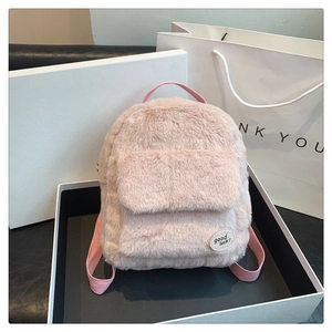 Primer plano de mochila de felpa rosa con parche Good Luck en una caja de regalo blanca