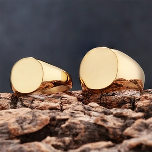 Macro shot of two polished gold stainless steel signet rings resting on textured wood bark