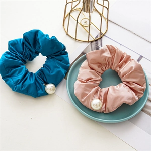 Detailed view of blue and pink satin scrunchies with elegant pearl pendants