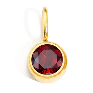 Macro detail of round red birthstone pendant in golden stainless steel bezel setting