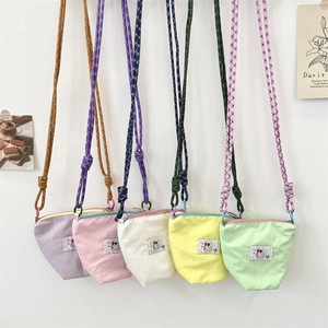 Detail of five macaron-colored crossbody canvas phone bags with woven rope straps