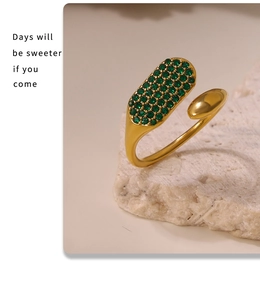 Détail d'une bague réglable dorée avec pavé de zircons verts et design en goutte