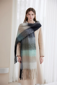 Macro detail of thick winter scarf featuring blue gradient plaid pattern and fringe