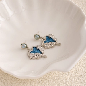 Vintage silver heart earrings with blue texture detail in a white shell bowl