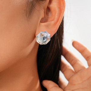 Close-up of a large hexagonal crystal stud earring with clear faceted glass on model
