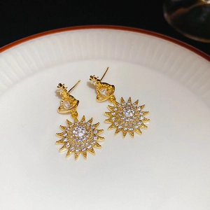 Macro shot of gold Saturn star stud earrings with pave crystals on white ceramic