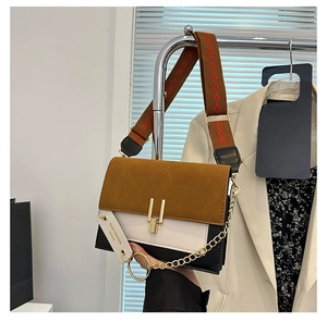 Detail of multi-color crossbody bag featuring suede textures and golden chain accents