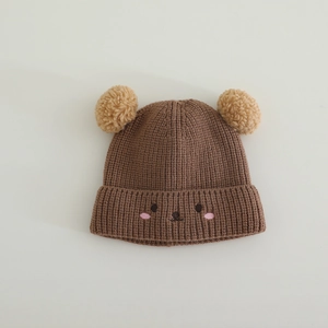 Detail of baby winter knit hat with cute bear embroidery and dual plush pom-poms