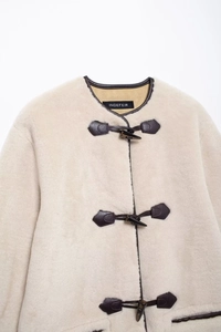 Détails du manteau en fausse fourrure avec liseré en cuir et fermoirs brandebourg