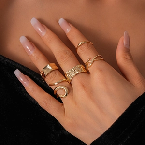 Close-up of golden geometric ring set with hammered texture and layered stacking style