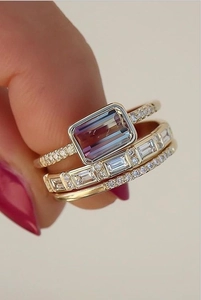 Macro shot of three-piece 18K gold ring set with emerald-cut gradient zircon and baguettes