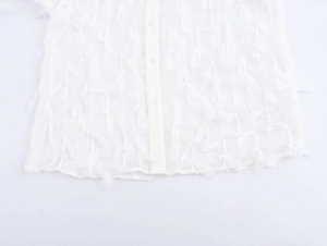 Detailed view of white translucent blouse featuring feather-like texture and buttoned placket