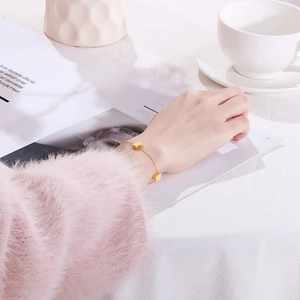 Close-up of gold heart charm bracelet on wrist with elegant lifestyle background
