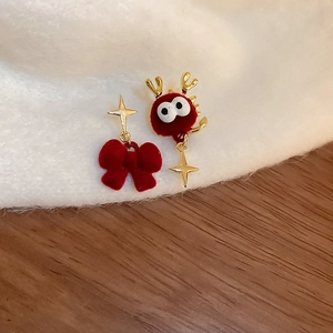 Détail macro de boucles d'oreilles nœud rouge floqué et monstre avec étoiles dorées