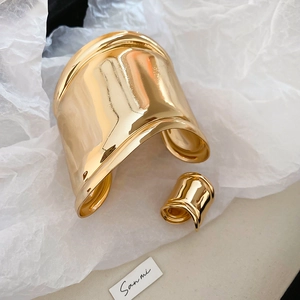 Detailed view of wide gold cuff bracelet and matching ring with polished wavy organic shapes