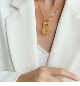 Détail du collier doré avec pendentif lettre B et fermoir épingle de marque pour femme
