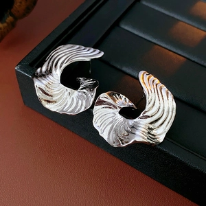 Close-up of silver earrings with textured wave pattern on a black jewelry display