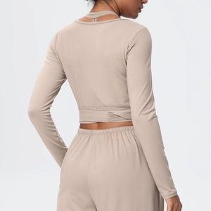 Detail of the cross-strap back design on beige long sleeve yoga top and high waist leggings