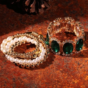 Detailed shot of vintage gold bracelet set featuring emerald green stone and pearls