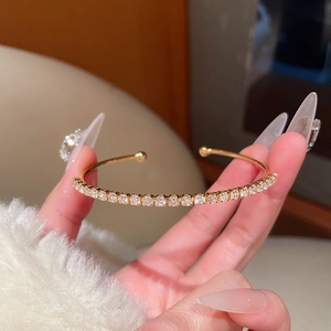 Detail of 18K gold plated open bangle with pavé-set shimmering zircon stones on hand