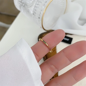 Detailed close-up of rainbow zircon row ring in 18k gold plating on model's finger