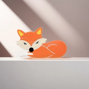 Gros plan sur la pince à cheveux renard orange en PVC posée sur une surface blanche
